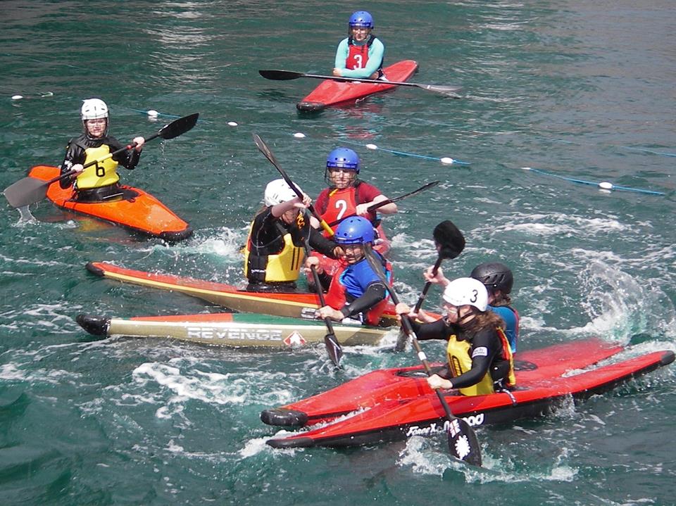 Canoe polo players paddling alongside one another during a game.