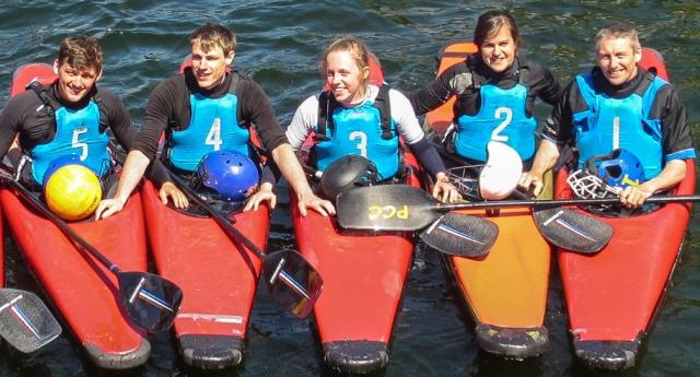Five paddlers in blue buoyancy aids sitting together in kayaks on the water.